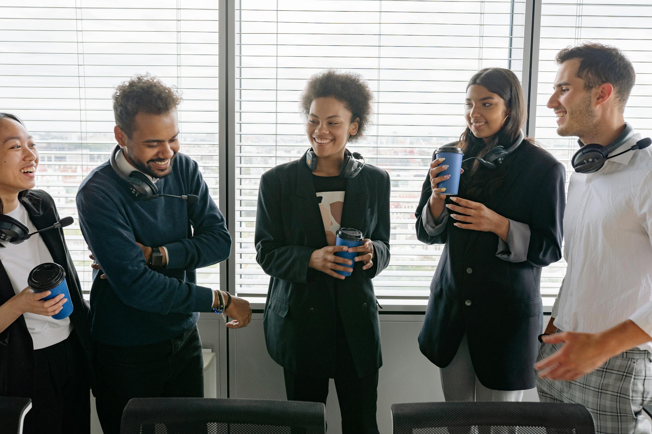 A diverse group of call center agents enjoying a casual break in the office, sharing laughs and hot drinks.
